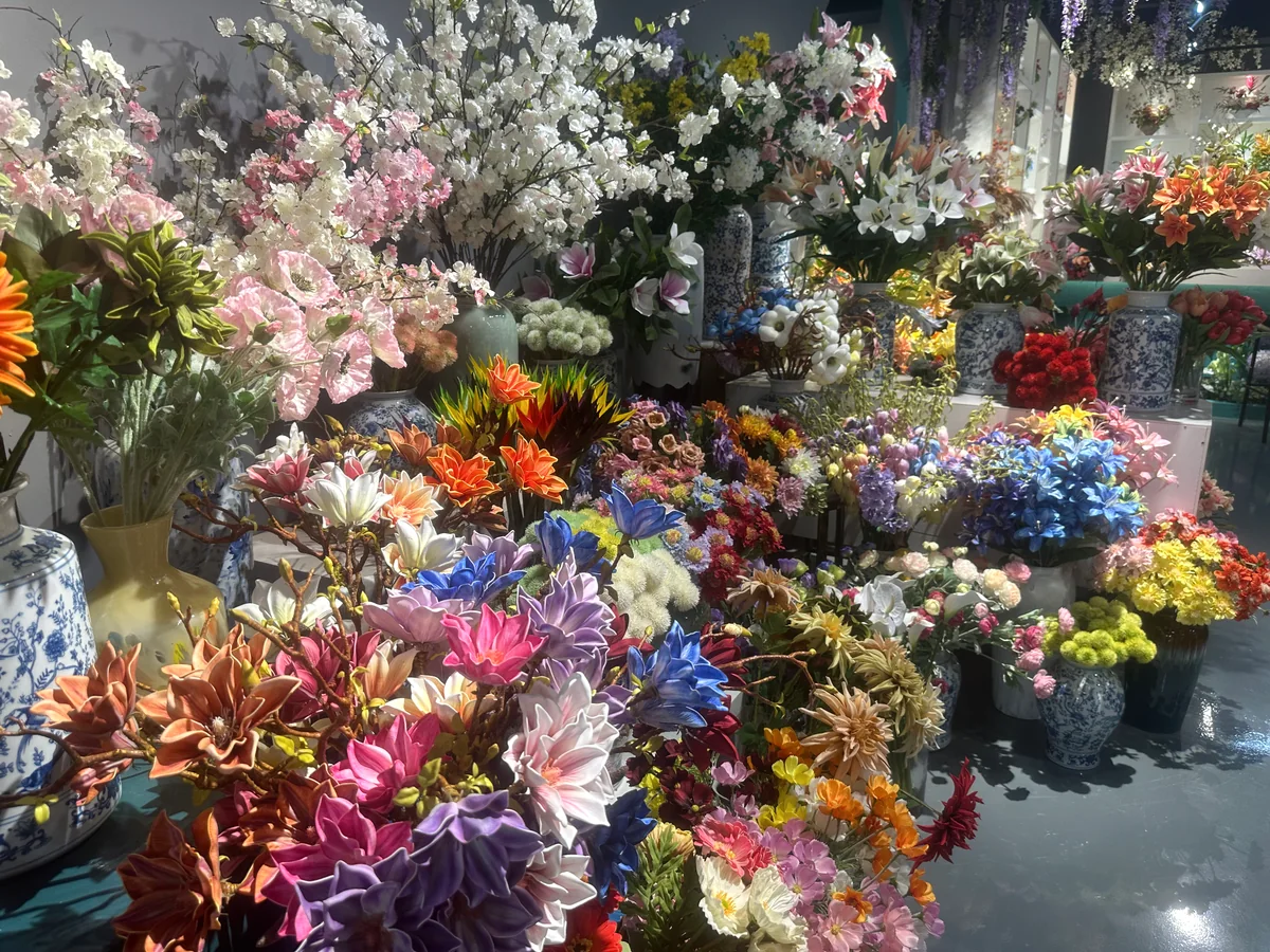 Mixed artificial flowers and blossom branches in white, pink, blue and orange displayed in showroom vases.