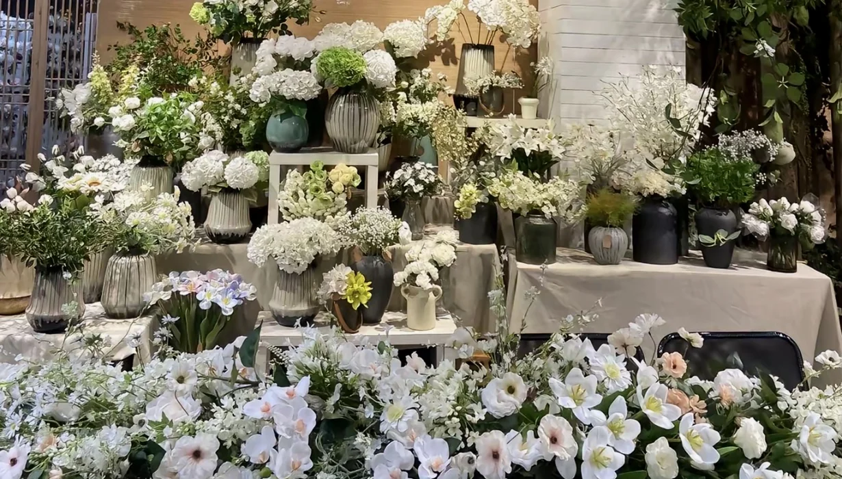 White artificial flower arrangements and greenery displayed in a showroom.