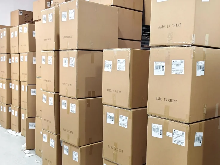 Sealed cardboard cartons with labels stacked in rows indoors.